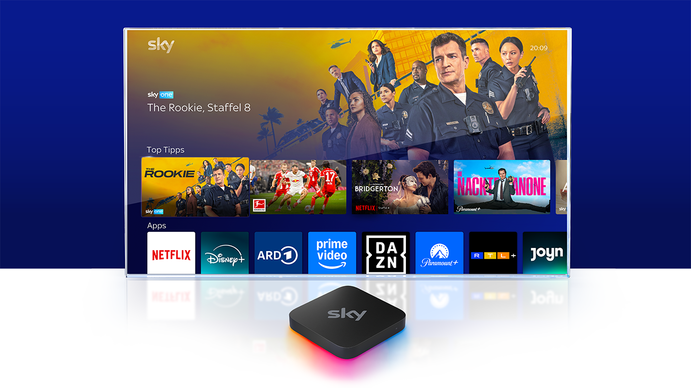 Sky Stream Box mit Fernseher im Hintergrund, der das User Interface des Geräts zeigt